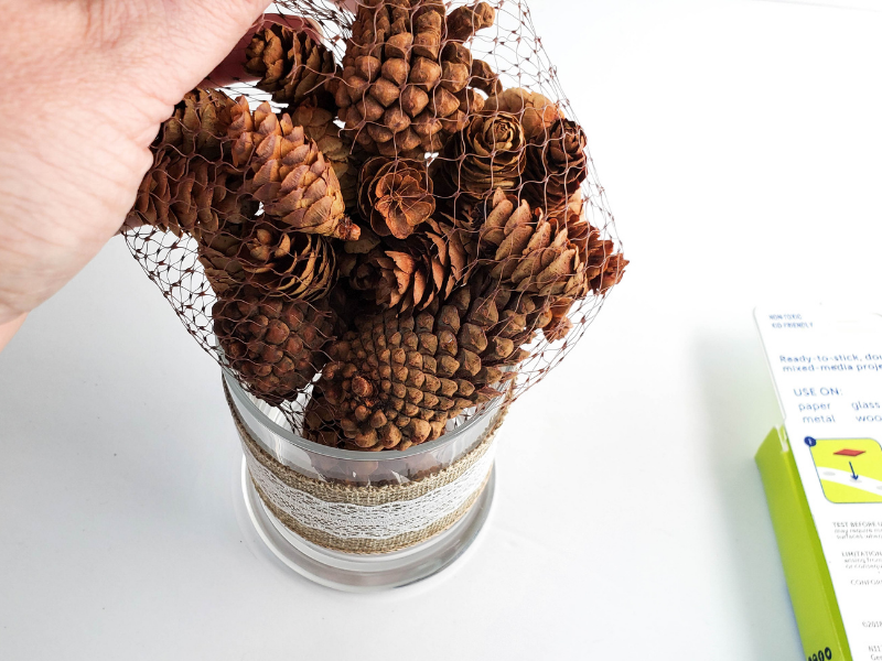 Adding the pine cones to make a Dollar Store Pine Cone Decoration