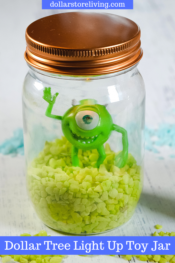 The finished version of the toy jar with Mike from Monsters Inc. on top of green pebbles sealed up in a plastic mason jar.