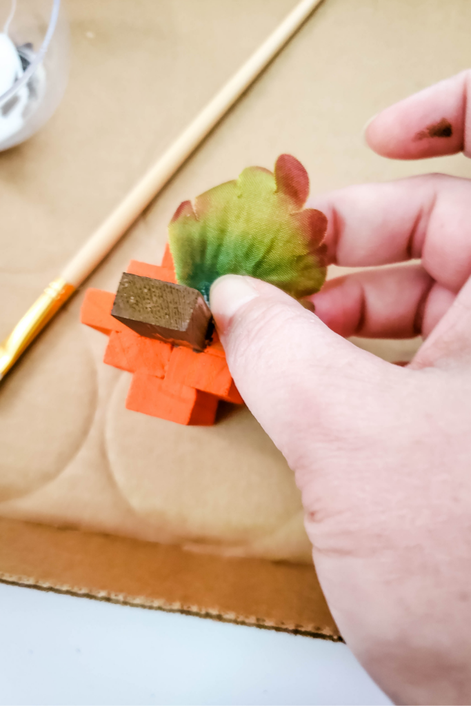 Adding a sunflower leaf to the painted jenga block pumpkin. 