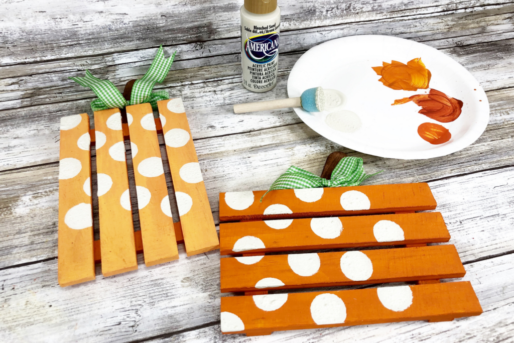 Painting white polka dots on the mini pallet pumpkins. 