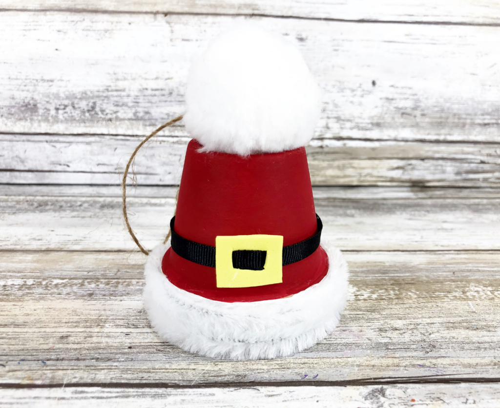 The completed Santa Hat Clay Pot Christmas Ornament on a wood background